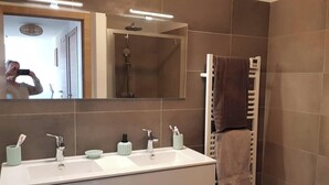 A bathroom with a large mirror, two sinks, a towel rack, and a shower. - 4-6 PERSON APARTMENT (Albitreccia)
