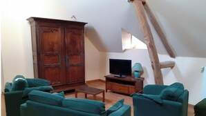 A living room with a wooden cabinet, a television, and two teal sofas.
