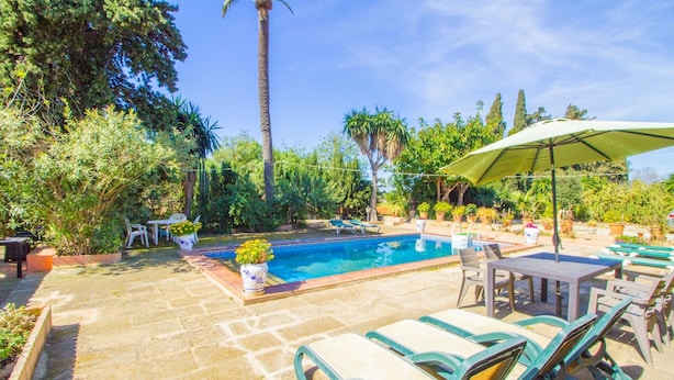 A pool area with lounge chairs, a table, and a covered umbrella.