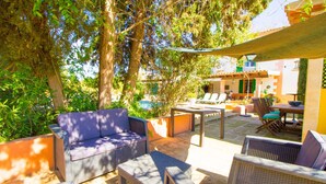 An outdoor patio with wicker furniture, a pool, and a building with a yellow facade.