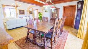 A dining area with a wooden table, chairs, a chandelier, and a large clock.