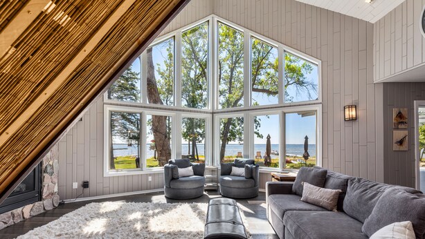Un salon moderne doté d’une grande fenêtre donnant sur un paysage magnifique, d’une cheminée et d’un coin salon confortable.