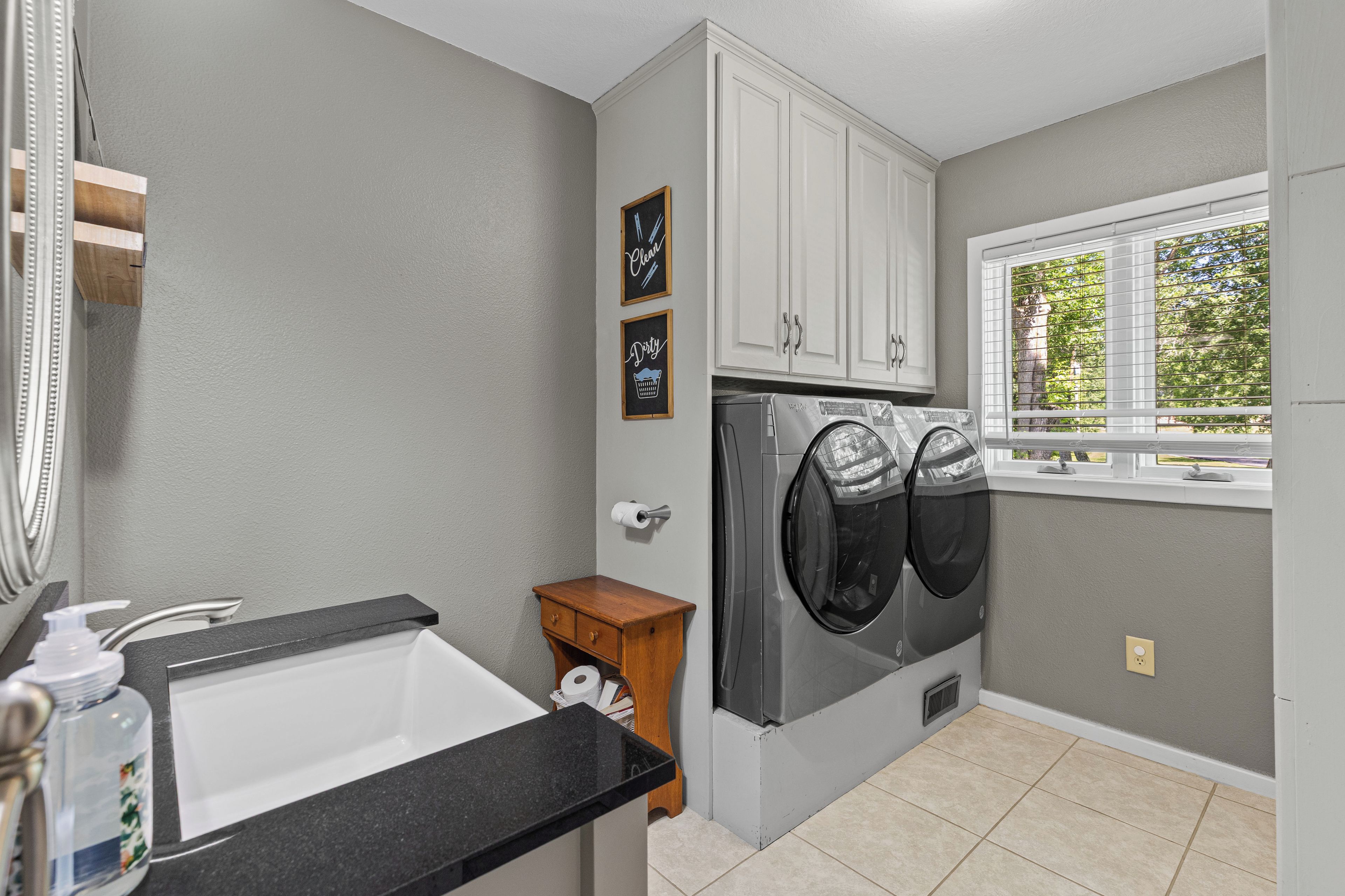 A laundry room with a washing machine, a sink, and cabinets.