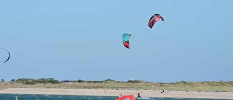 A beach with clear skies and three kites flying.