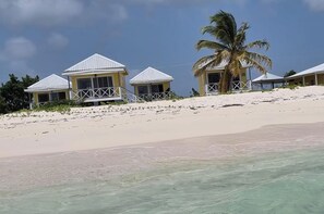 A beachfront property with multiple bungalow-style buildings, each with a white roof and a balcony.