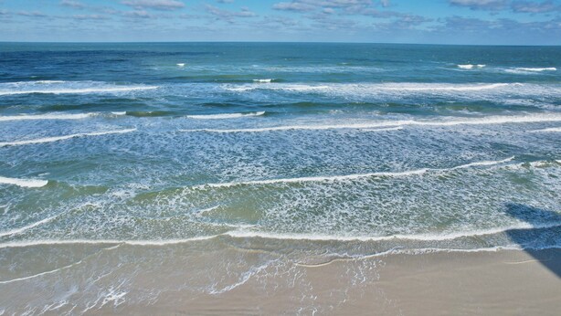 Una playa con olas acercándose a la orilla.