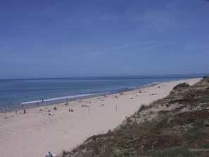 Ein Strand mit badenden und sonnenbächelnden Personen.