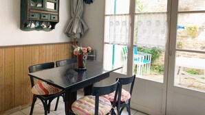 A dining area with a wooden bench, a black table, and a cabinet with dishes. - Apartment SAINTE CLAIR (Saint-Martin-de-Ré)