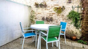 A round table with four chairs, a white wall, and potted plants. - Apartment SAINTE CLAIR (Saint-Martin-de-Ré)