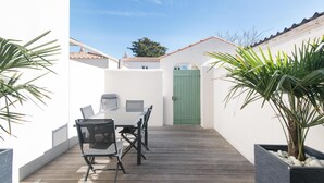 A patio with a table and chairs, a green door, and potted plants.