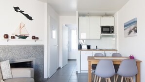 A modern kitchen with white cabinets, a microwave, and a dining area with a wooden table and chairs.