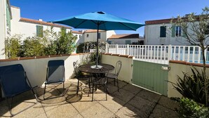 A patio with a table and chairs, an umbrella, and a white fence.