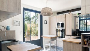 Een moderne keuken met een groot raam, inbouwapparatuur en een hanglamp.