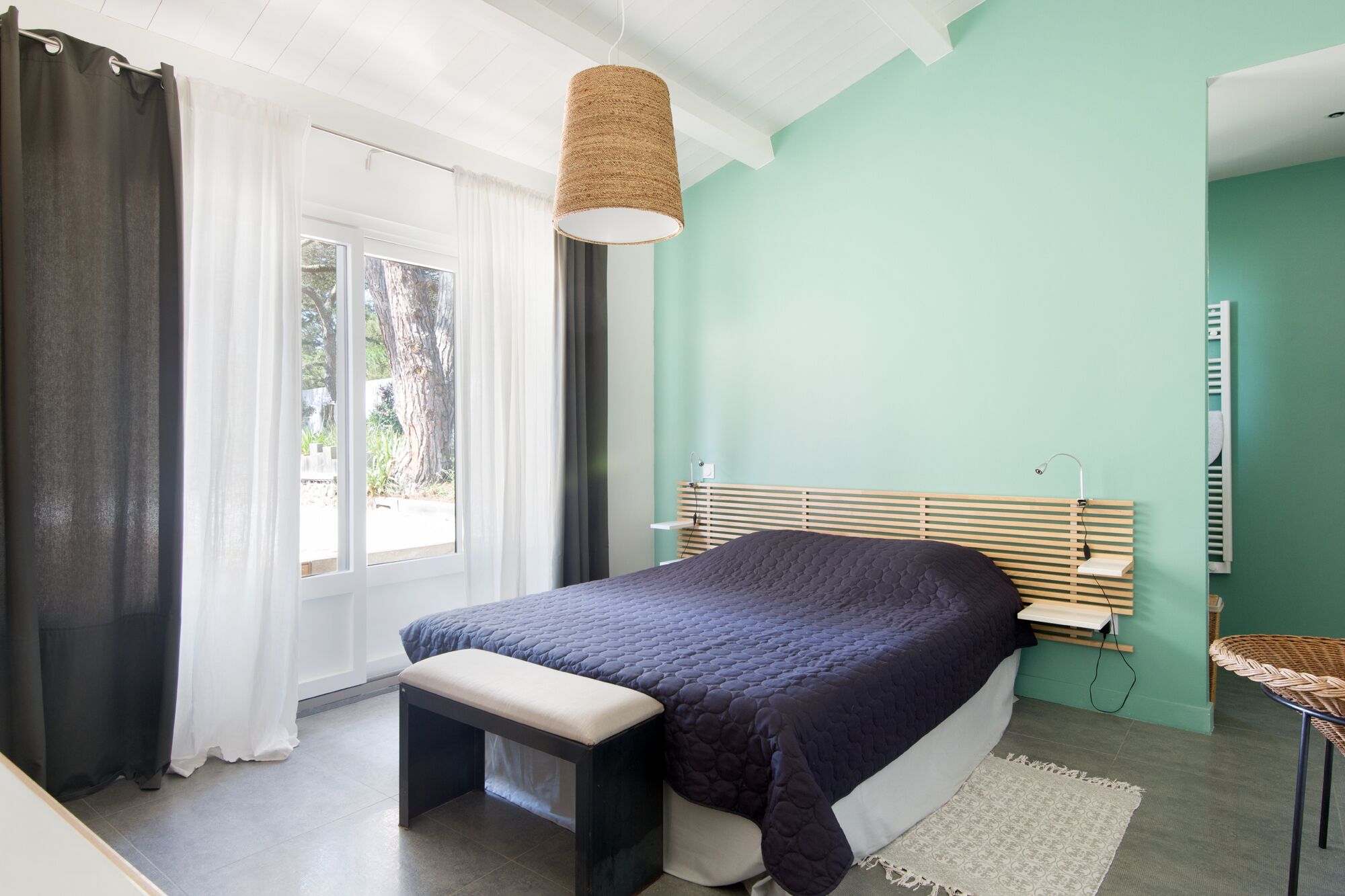 Ein Schlafzimmer mit Bett, Bank und Pendelleuchte.