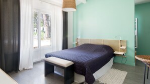 Een slaapkamer met een bed, een bankje en een hanglamp.