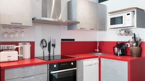 Una cocina moderna con encimeras rojas, electrodomésticos de acero inoxidable y un microondas instalado en la pared.