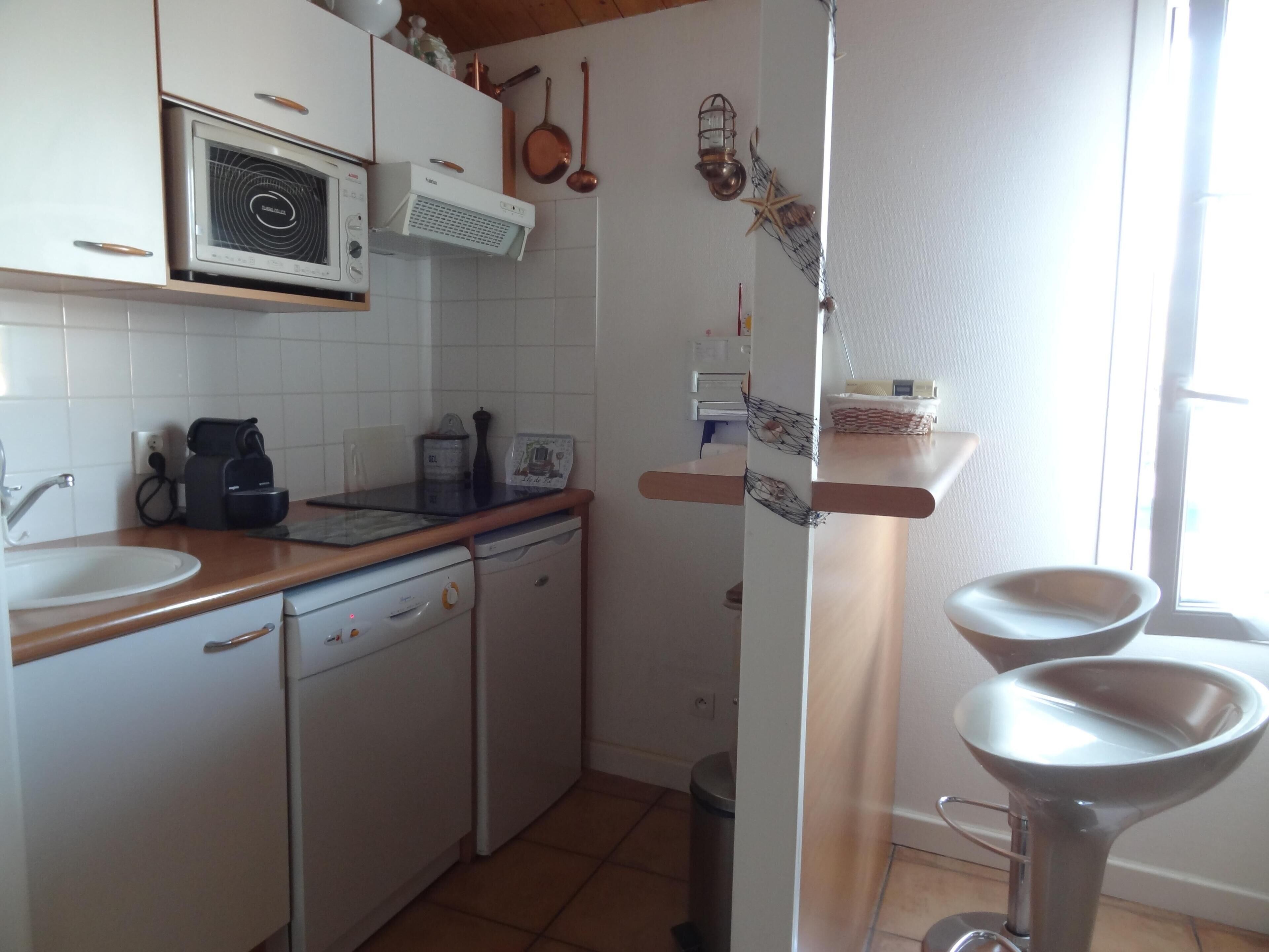 A kitchen with white cabinets, a microwave, a coffee maker, and a sink.