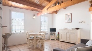 Un salón amplio con una mesa de comedor, sillas, un sofá, un televisor y un armario.