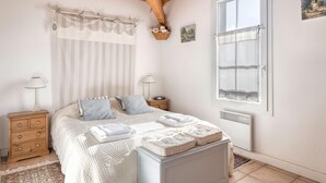 Un dormitorio con cama, mesitas de noche, ventana y radiador.