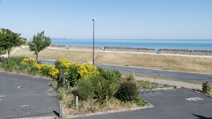 Un parking offrant une vue sur la mer et bordé d’un mur de pierres.