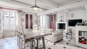 A modern living room with a dining area, white furniture, a fireplace, and a TV. - House SALICORNE    . (La Flotte)