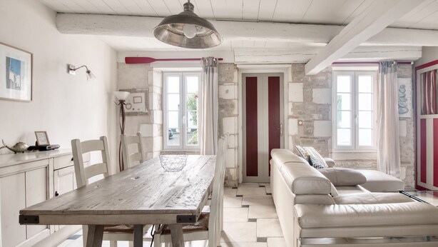 A spacious room with a wooden dining table, white chairs, a sofa, and a hanging light fixture. - House SALICORNE    . (La Flotte)