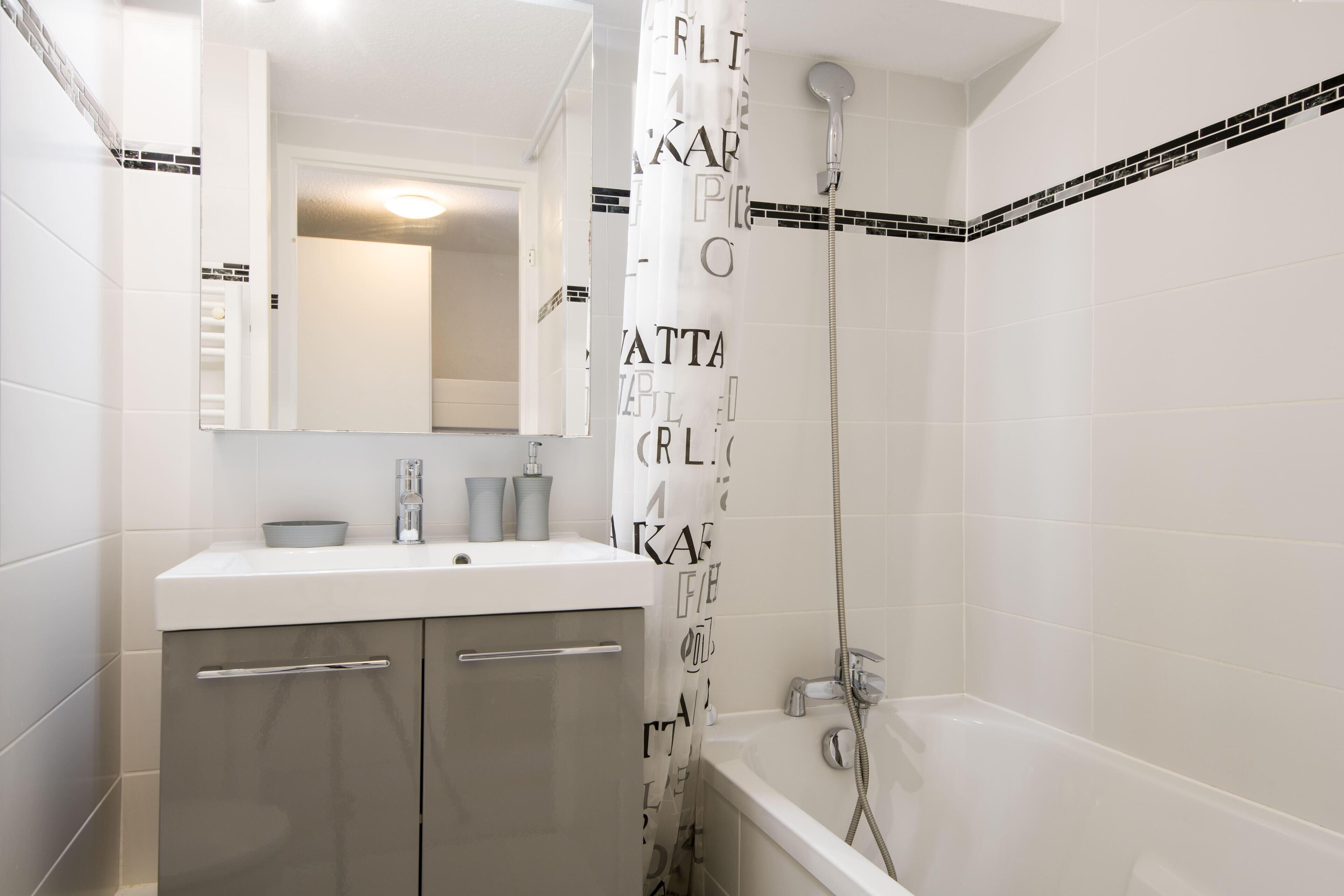 Une salle de bain moderne avec un lavabo blanc, un miroir et une douche.