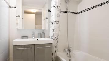 Une salle de bain moderne avec un lavabo blanc, un miroir et une douche.