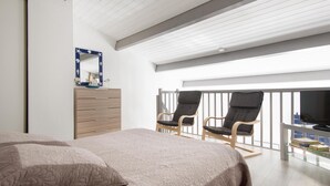 Ein Schlafzimmer mit Bett, Schminktisch, Spiegel, zwei Stühlen und einem Fernseher auf einem Balkon.