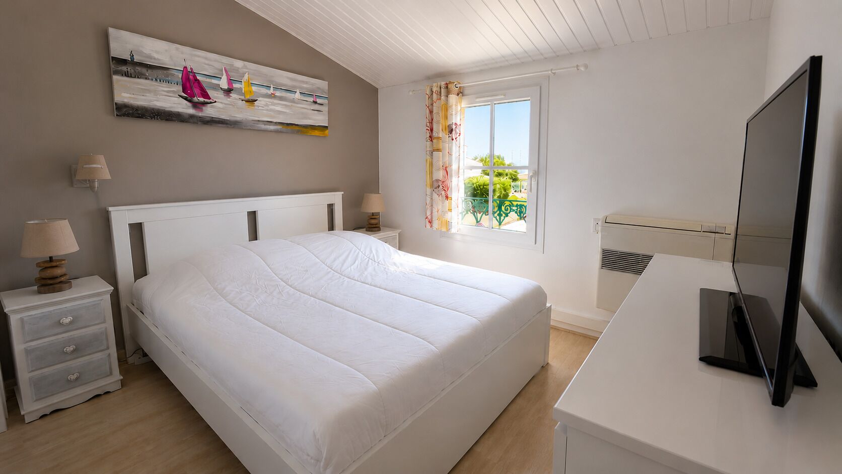 A bedroom with a bed, bedside tables, a TV, a window with curtains, and a painting on the wall.