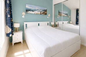 Ein Schlafzimmer mit einem großen Bett, einem Nachttisch, einem Spiegel und Wandbildern.