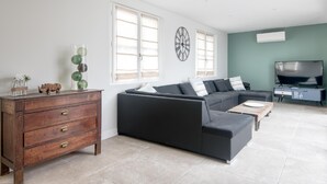 Ein modernes Wohnzimmer mit einer Eckcouch, einem Holzschrank und einem Flachbildfernseher.