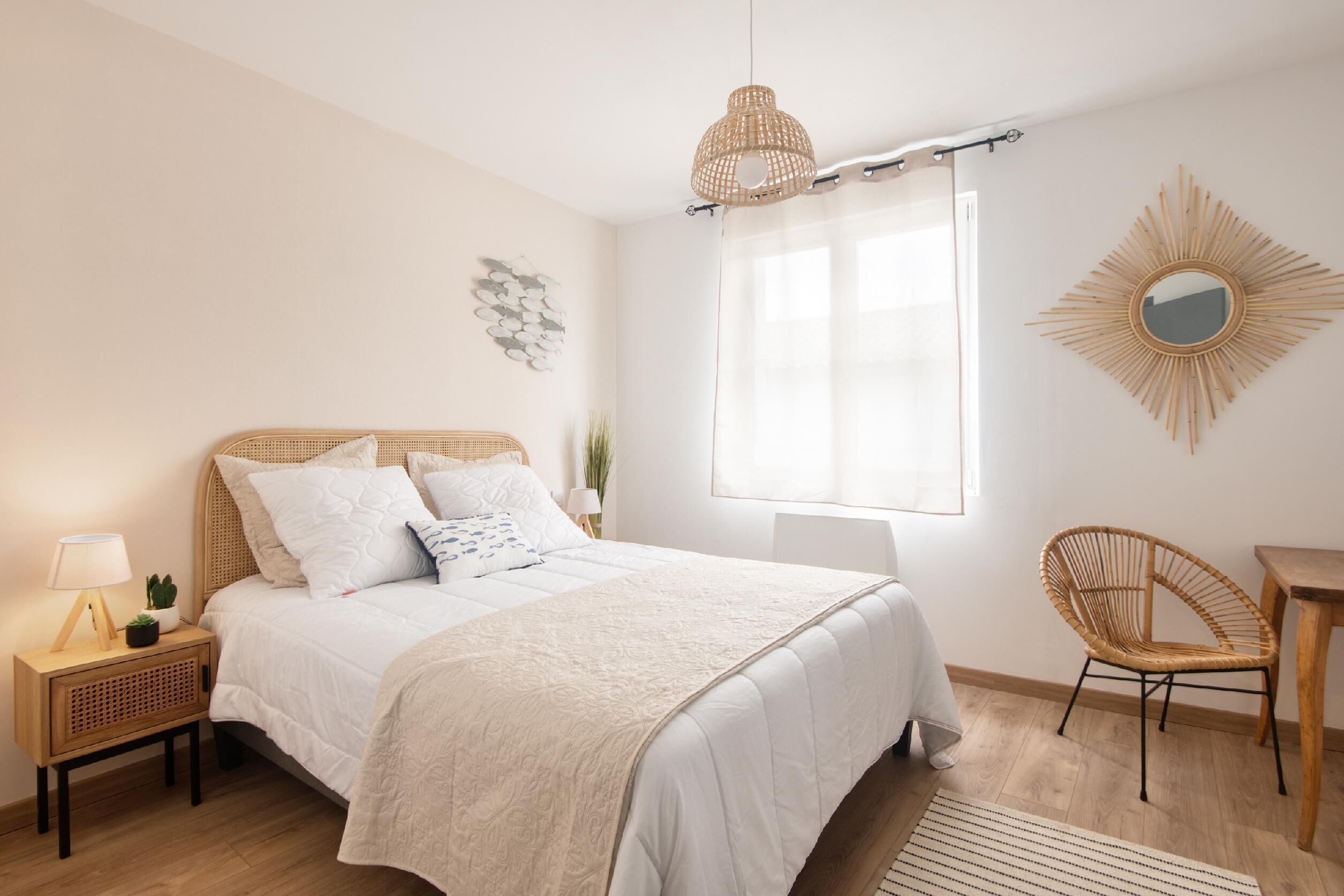 A bedroom with a bed, bedside table, lamp, and a chair.