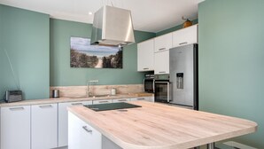 Eine moderne Küche mit weißen Schränken, einem Edelstahlkühlschrank und einer Holz Arbeitsplatte.