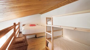 Une chambre de dortoir avec des lits superposés, un plafond en bois et un plancher en bois.