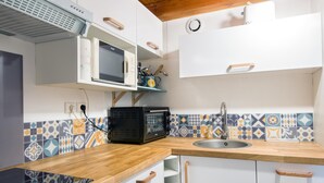 Une cuisine avec des armoires blanches, un plan de travail en bois, un four à micro-ondes, un grille-pain et un évier.