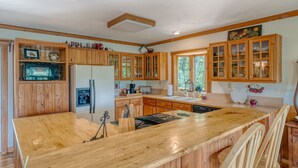 Una cocina amplia con armarios de madera, una isla central y un gran ventanal que aporta luz natural.