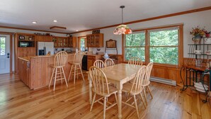 Una cocina con armarios de madera, una mesa de comedor con sillas y un ventanal grande.