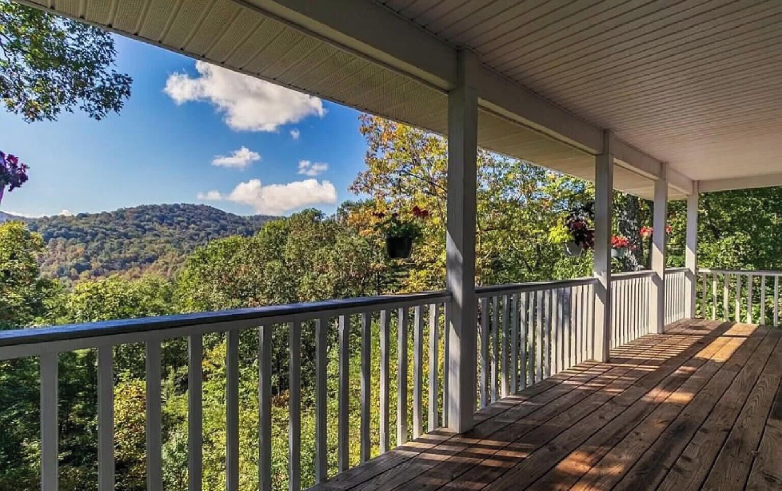 A wooden deck with a white railing overlooking a mountainous landscape.