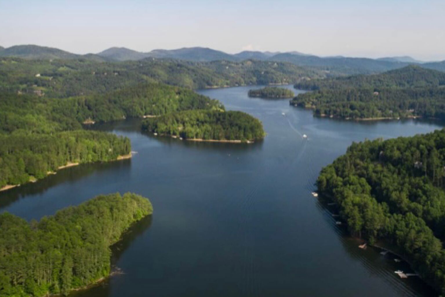 An aerial view of a lake surrounded by forested hills.