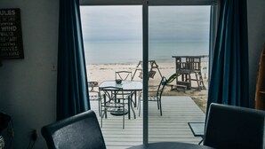 Une pièce avec vue sur la plage, une table et des chaises, et un panneau accroché au mur.
