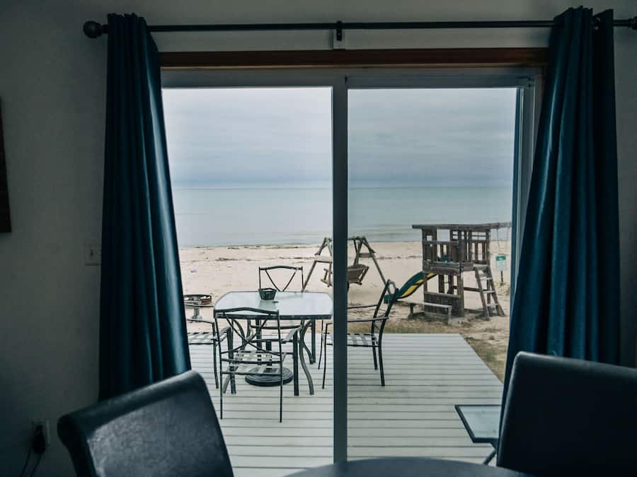 Una habitación con vista al mar, una mesa y sillas, y un cartel en la pared.