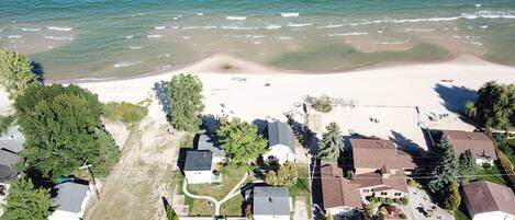 An aerial view of a coastal residential area with houses, a beach, and a parking lot.
