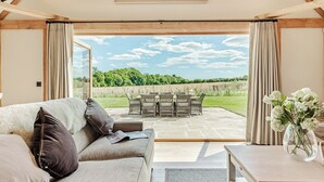 Una habitación acogedora con sofá, una mesa y vistas a un jardín a través de un ventanal.