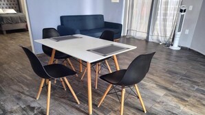A dining area with a table and four chairs, a blue sofa, and a standing heater.