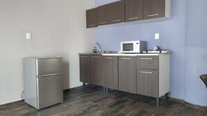 A modern kitchen with a built-in microwave, a stainless steel refrigerator, and dark wooden cabinets.