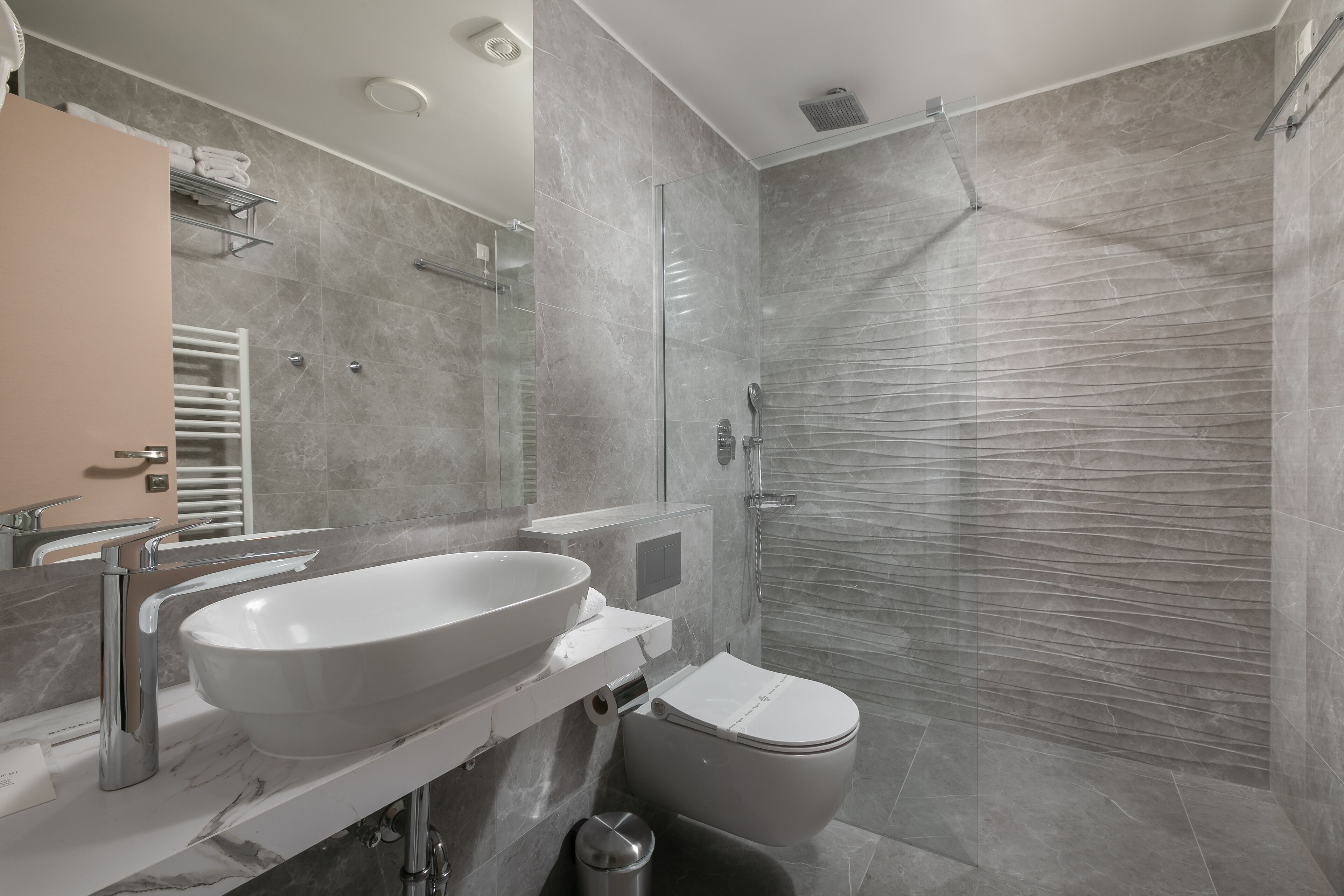 A modern bathroom with a large sink, toilet, and glass-enclosed shower.