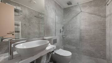 A modern bathroom with a large sink, toilet, and glass-enclosed shower.