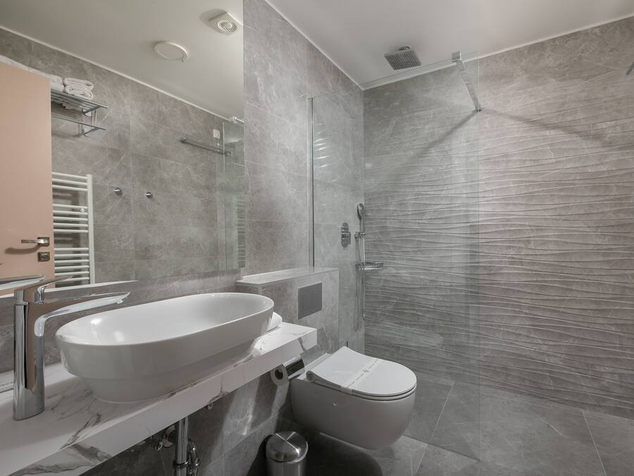 A modern bathroom with a large sink, toilet, and glass-enclosed shower.