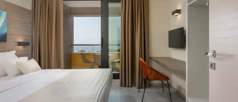 A hotel room with a bed, a TV, a desk, and a balcony with a view.